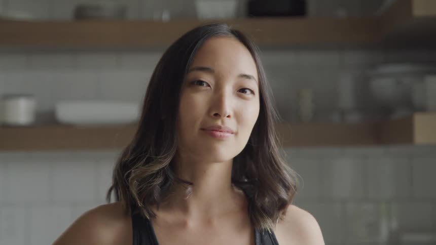 A woman blinks and then lightly smiles at the camera