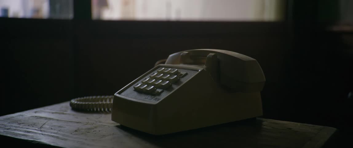 Retro push button telephone sitting on a table in a darkened office