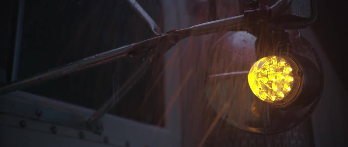 Rain falling on a side view mirror of a vehicle at night