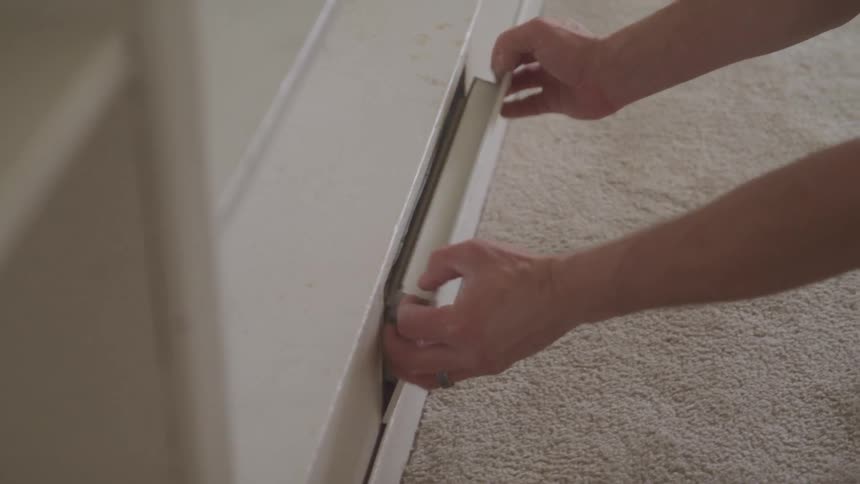 Man removes the cover from a vent near the carpeted floor