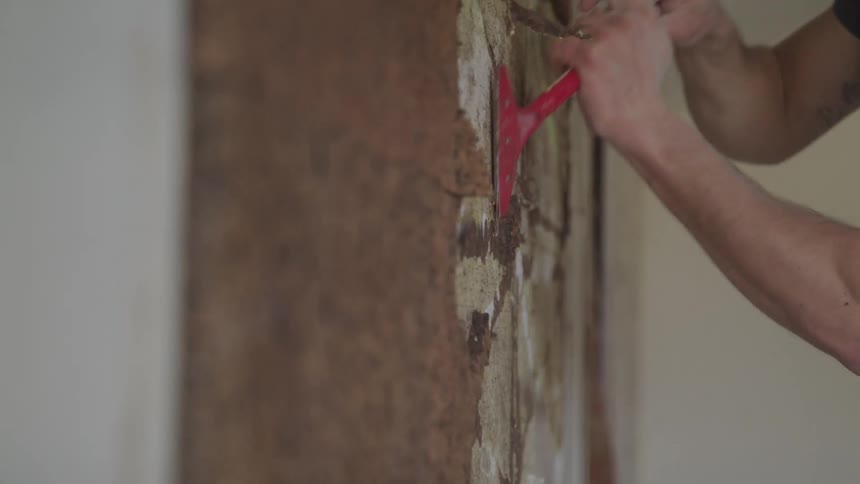 A person scrapes at a wall