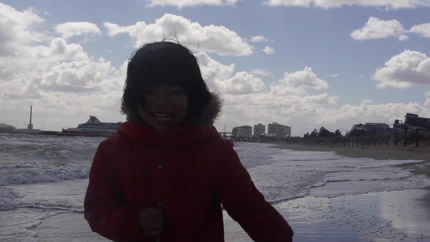 Child in a coat running on the beach