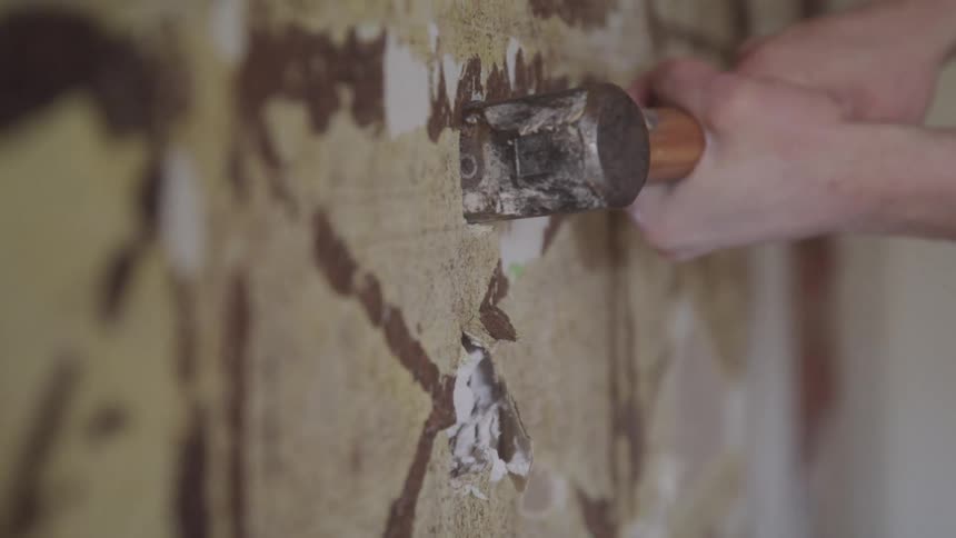 A construction sledgehammer breaking a wall