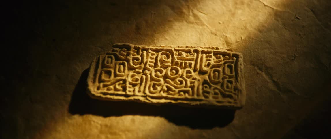 The camera pans down on a piece of ancient artwork