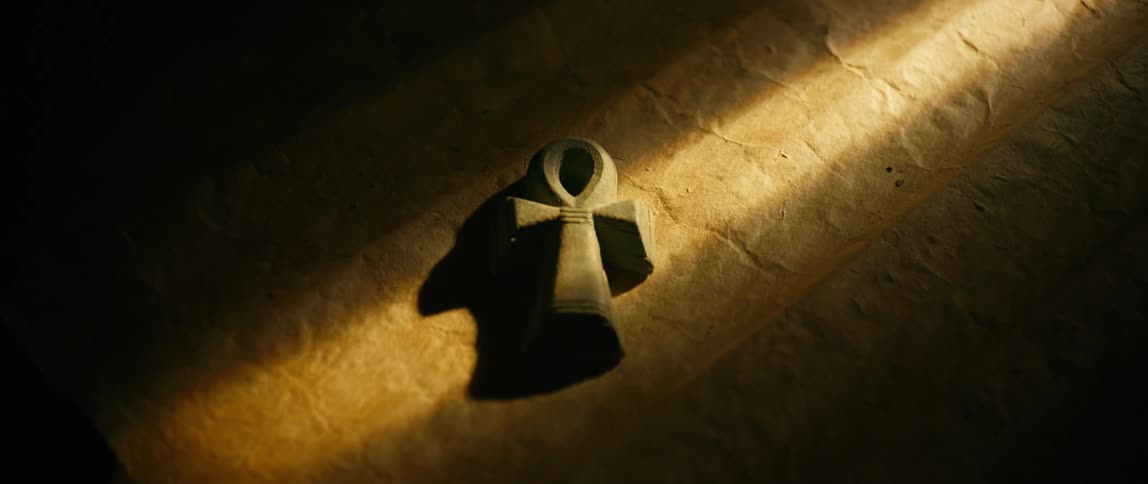 Sunlight shines onto an ank lying on a textured surface in a dimly lit room
