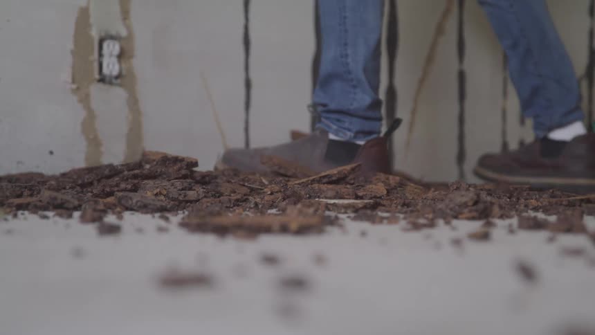 A construction worker is scraping the walls at a construction site