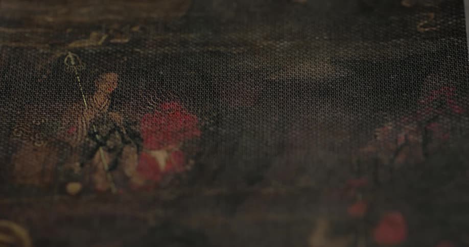 Closeup of an art painting on canvas depicting a person holding a staff standing beside a seated figure in a dimly lit setting