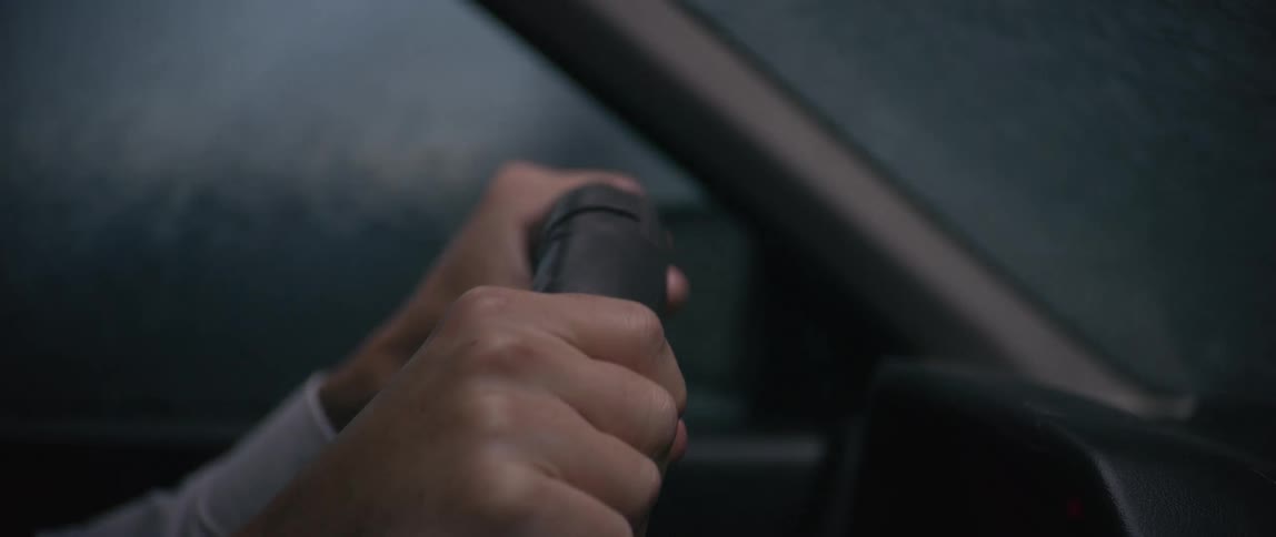 Distressed person gripping the steering wheel while driving in heavy down pouring rain