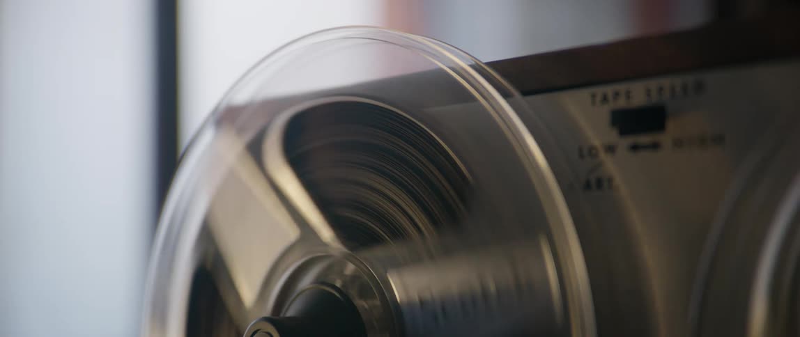 Transparent spools rotate on a reel to reel player