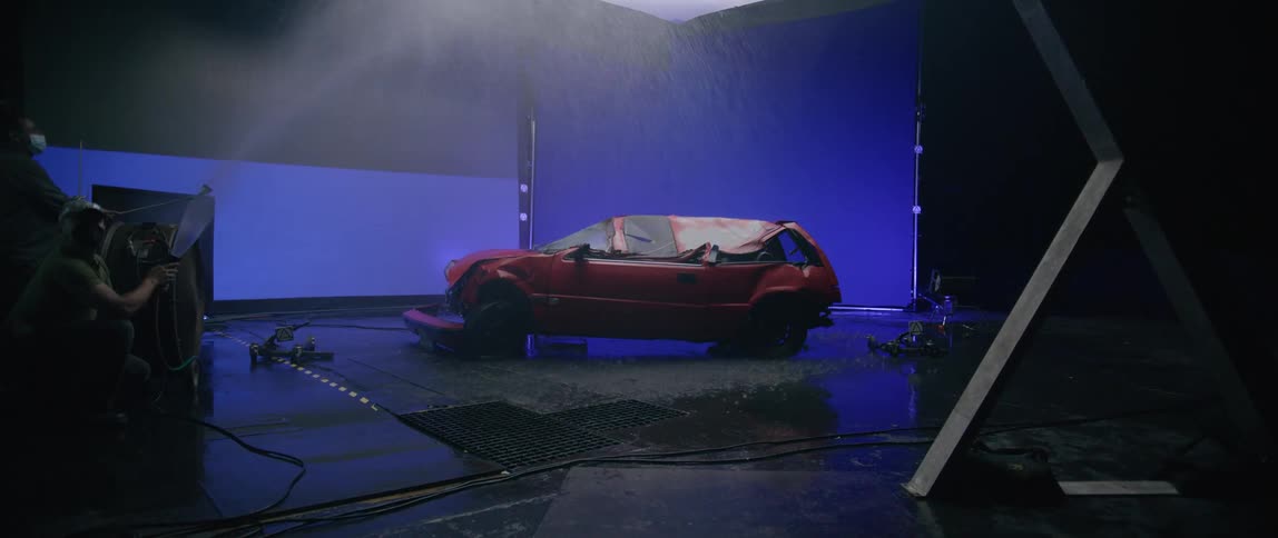 A man is spraying a hose on the destroyed car on stage
