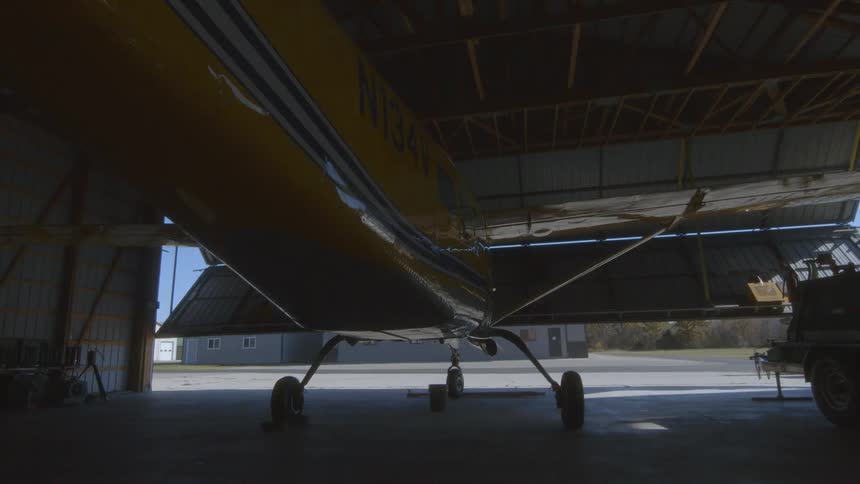 A small airplane is parked in a hangar as the door slowly opens