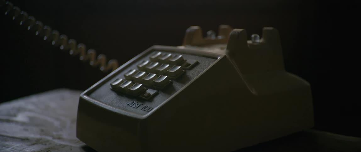 A hand picks up a phone off the receiver