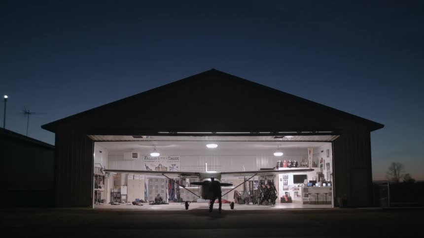 A person examines a plane parked in a hangar at night