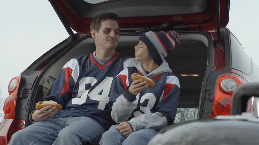 A man and son eat hot dogs in their car