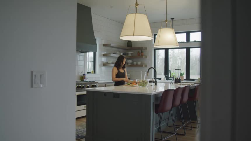 A woman chops food at her kitchen counter