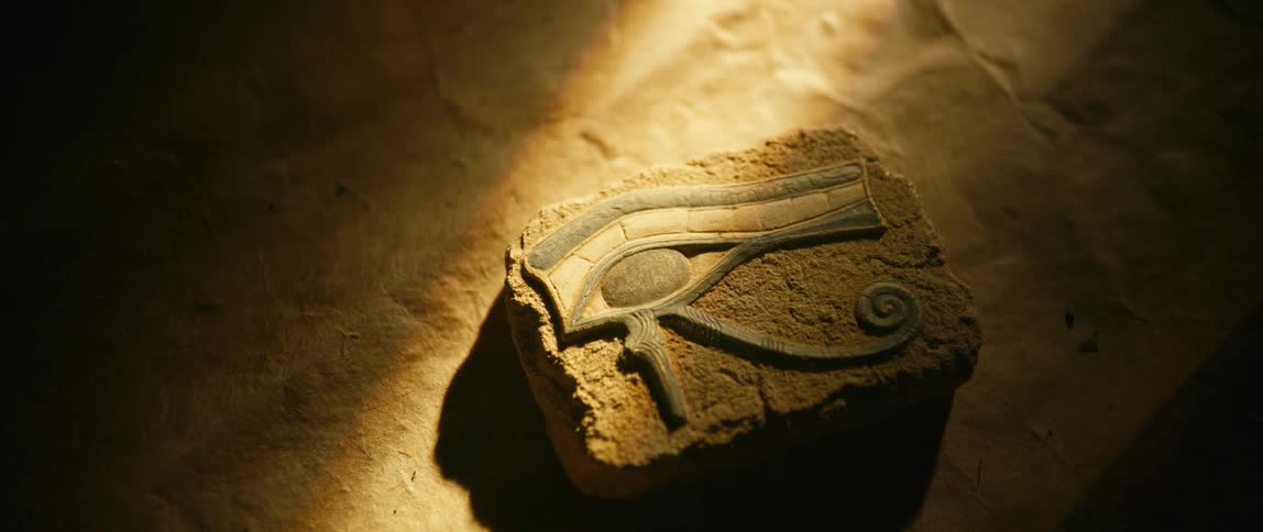 The eye of horus hieroglyph sculpted on a piece of stone lying in the sand