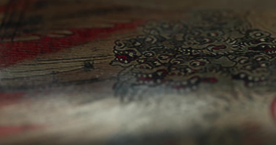 Detailed figures of mythical creatures with sharp teeth and fierce expressions adorn a wooden surface or canvas