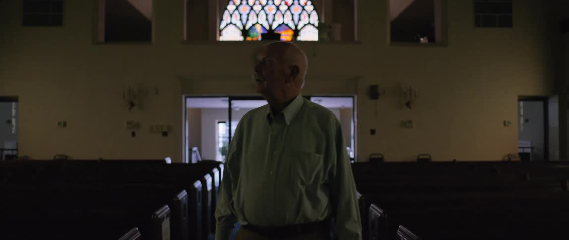 Elderly man looks around while walking through a church during the daytime