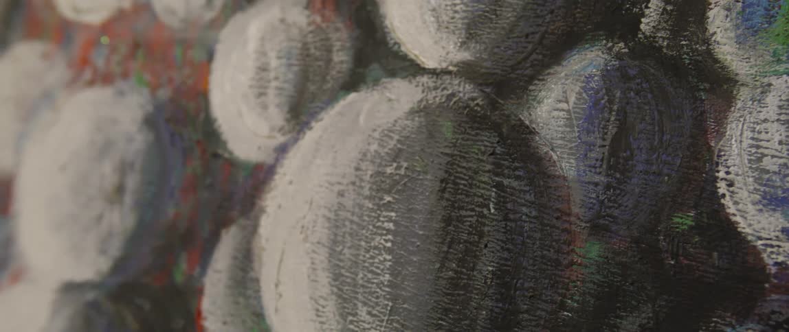 Close up of a textured brush painted canvas featuring white orb like shapes