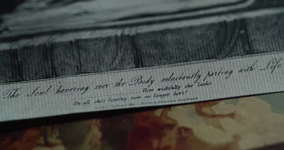 A piece of art with a quote in cursive on the bottom lays on top of another piece of art
