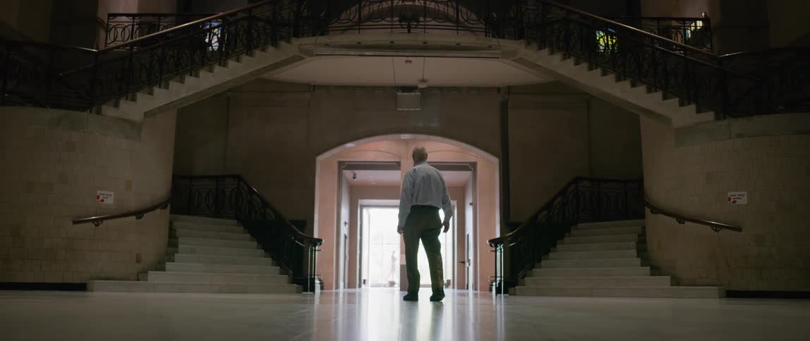 An older man is looking at the interior of an empty mansion