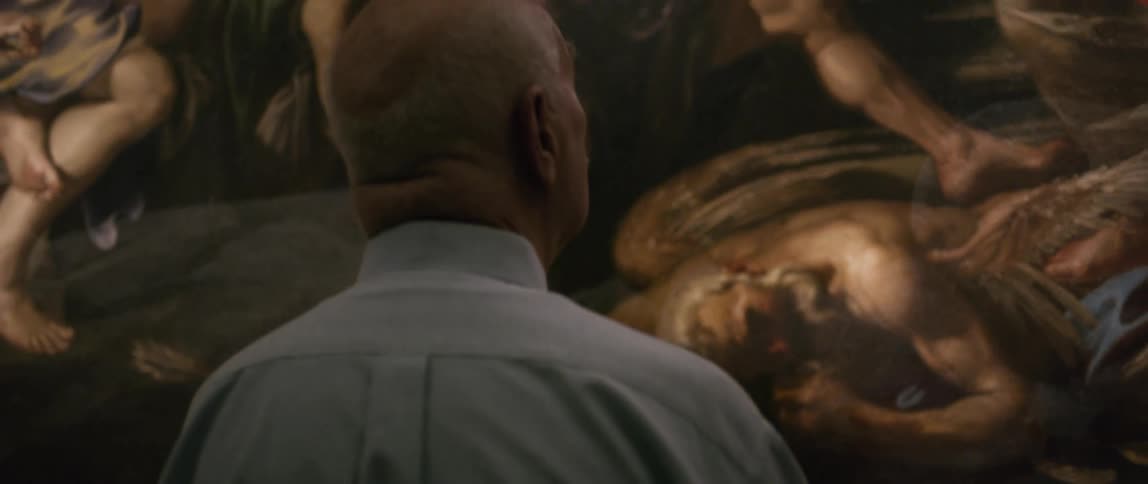 An elderly man wearing a grey shirt is looking at a large canvas painting in a museum