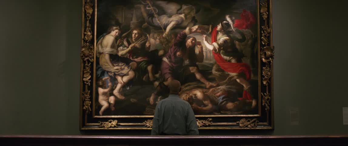Back of a man staring at a large painting in a museum