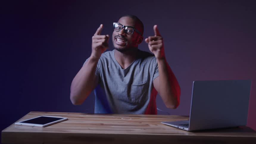 Man giving a lecture sitting at a table with a laptop a tablet