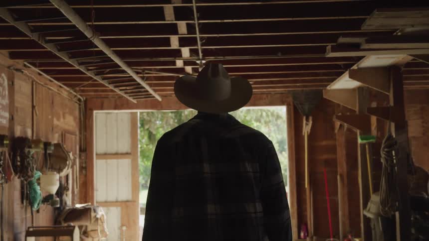 A cowboy walking out of a stable