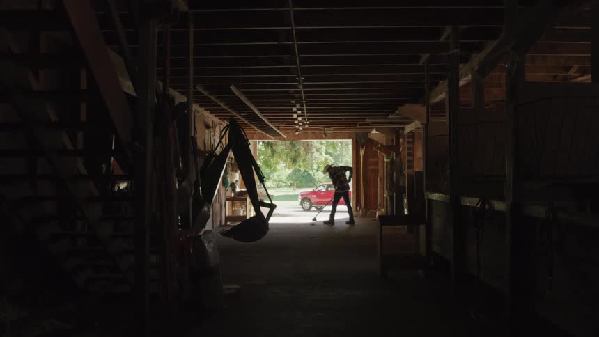 A man sweeps the inside of a barn