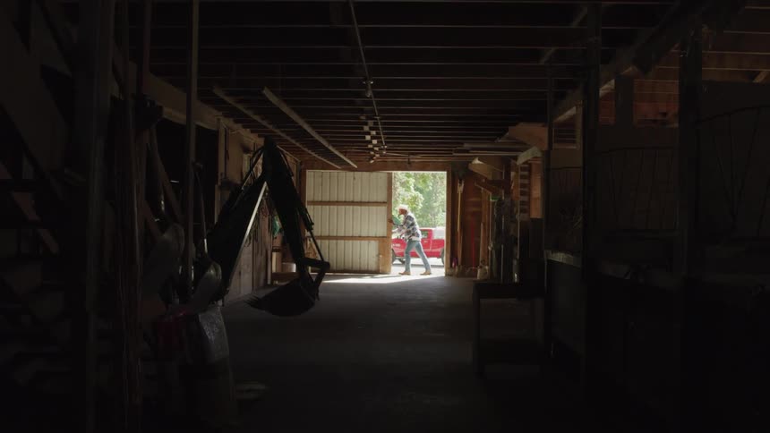 A man wearing a cowboy hat is pushing a garage door open