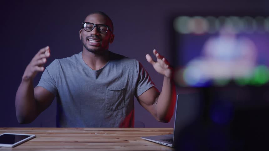 Man sitting at a table in a room recording a video