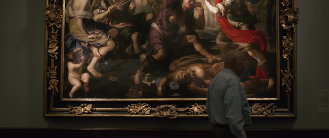 An elderly man stops to observe a piece of art then walks away