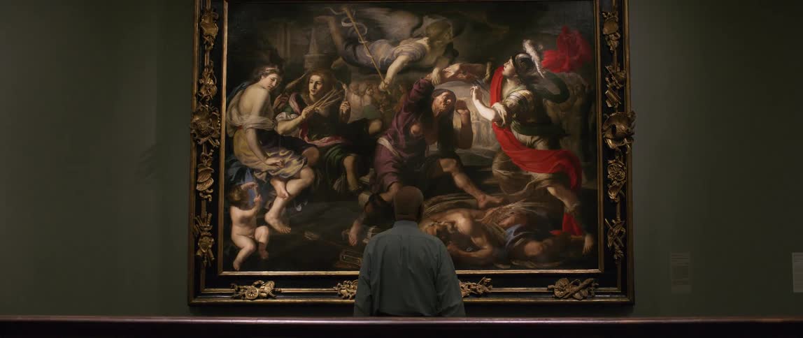 A man looks up at a large painting on the wall