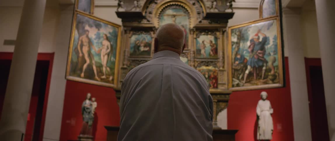 A man is viewing paintings in the museum