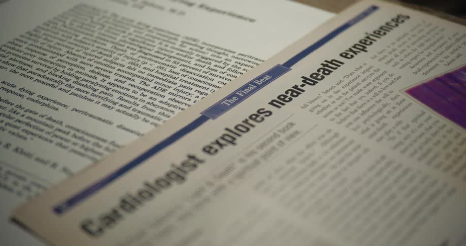A newspaper publication about a near death experience is laid out on a desk