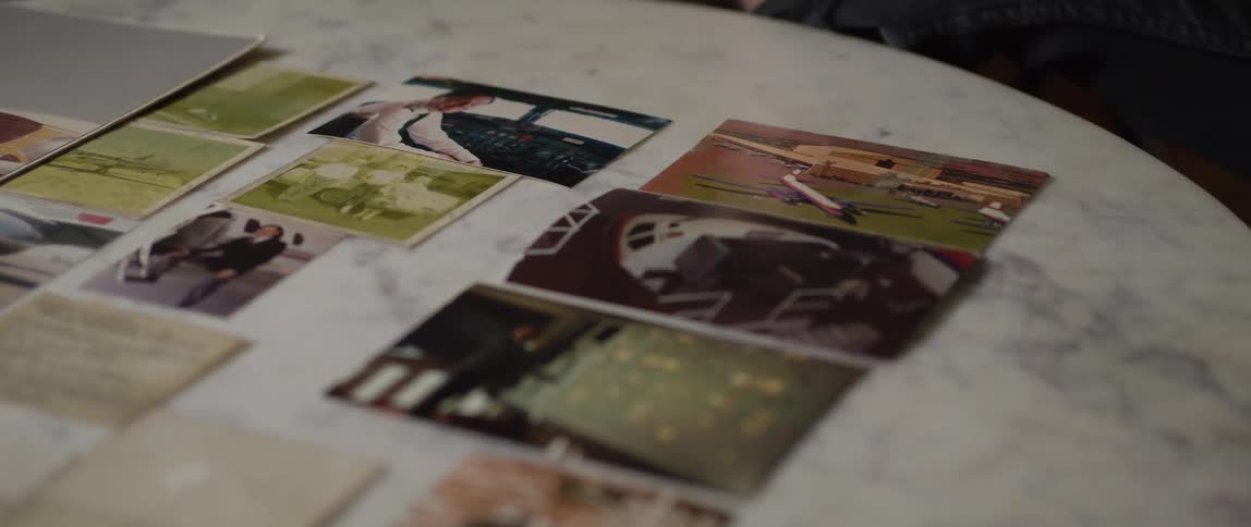 Several color photographs and documents displayed on a round grey marble table