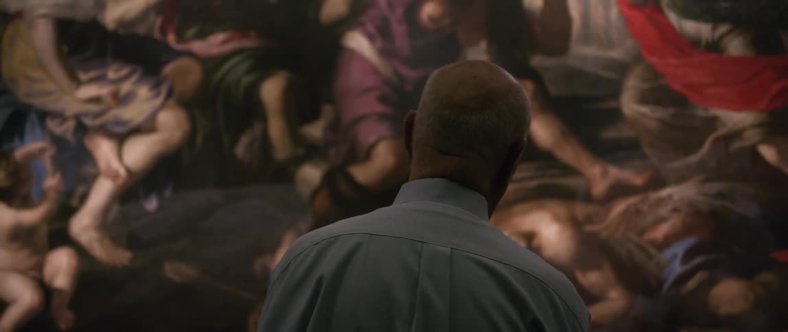 An elderly man standing in front of a piece of art simply observing