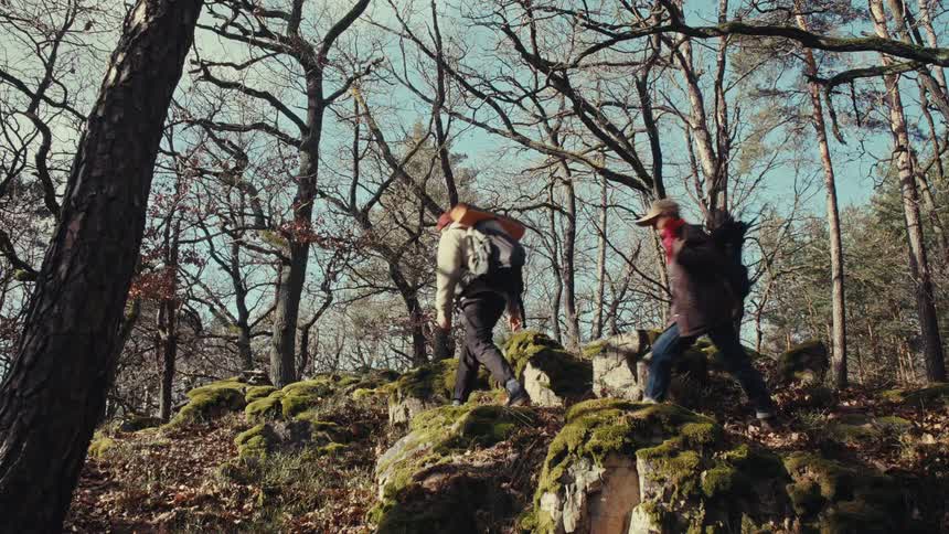 Couple backpacking across a mossy trail through the forest at miday