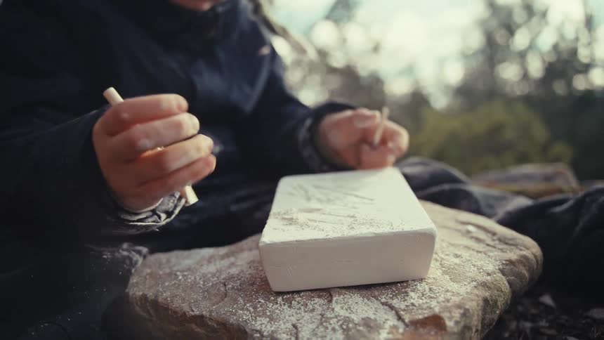 A boy is carving into a block