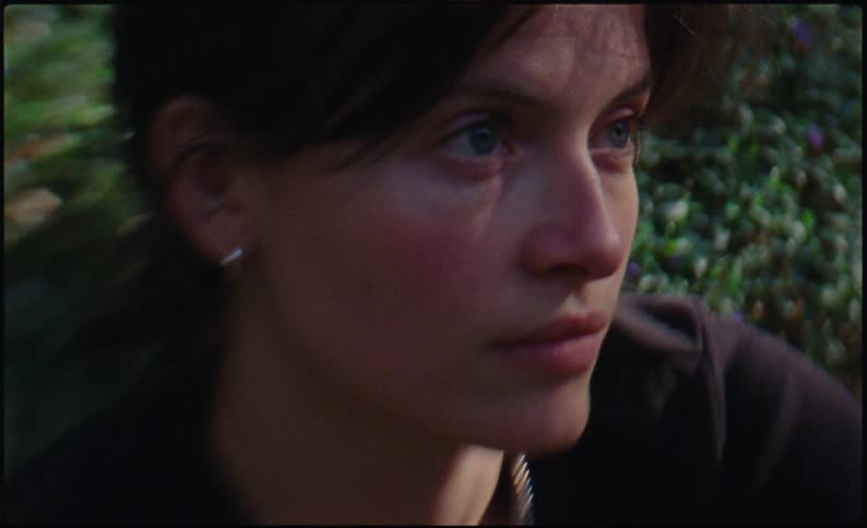 A woman is sitting near a bush