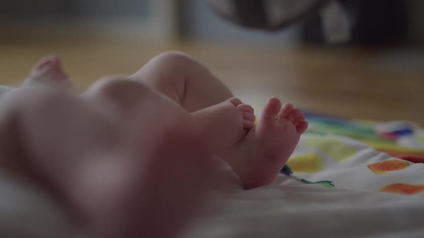 Close up of baby feet with painted toenails resting on a textured colorful blanket