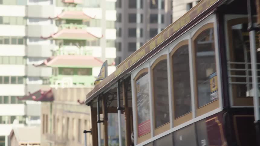 A streetcar full of people climbing up a hill in a metropolitan area