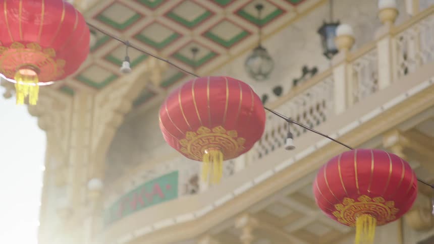 A series of red lamps hanging on a line to decorate the street seen at midday