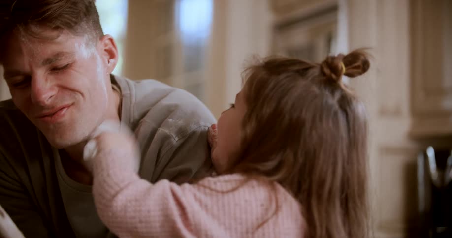 A child cleaning their fathers face both smiling and having fun
