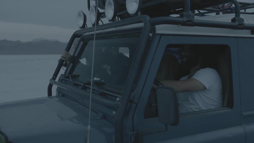 Vehicle driving through the desert while a man takes photographs