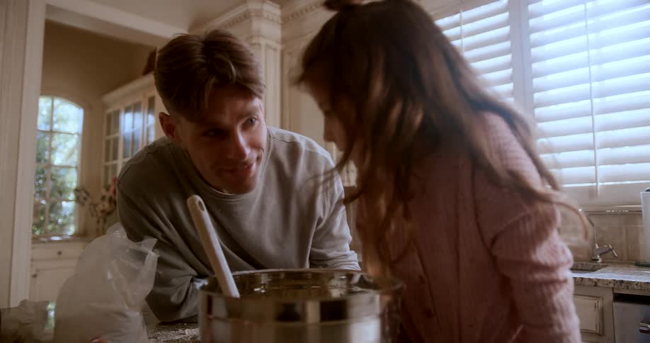 A father and daughter smile while looking into a pot of food