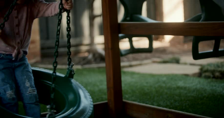 Child sitting on a toy tire in a playground and having fun