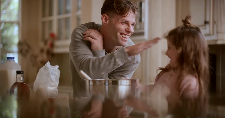 A father in the kitchen with his daughter playing with flour
