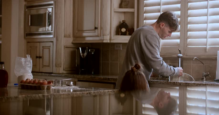 Father talks to his daughter while washing a mixing bowl in the sink